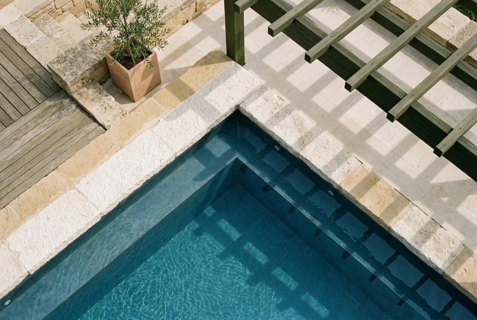 Close view of pool water over a pale mosaic surface with sunlight patterns
